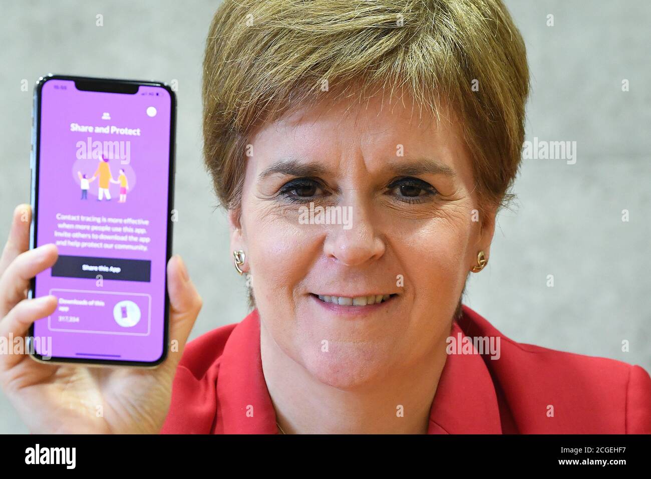 Il primo ministro Nicola Sturgeon vede la nuova app Covid-19 su un telefono al Parlamento scozzese di Edimburgo. Foto Stock