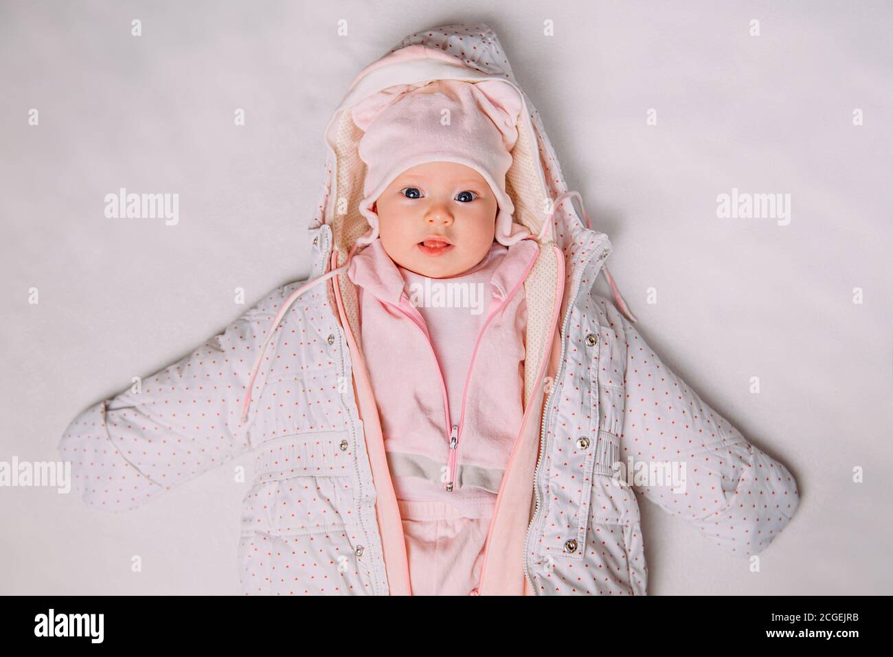 Bambina vestita come una cipolla. Vista dall'alto di un bambino carino in  un vestito bianco e rosa e un cappuccio ridente, sdraiato nella neve Foto  stock - Alamy
