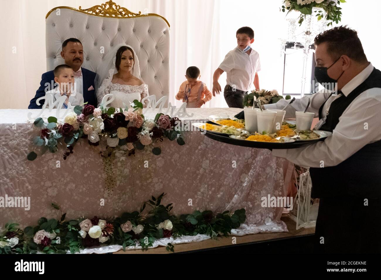 la coppia di nozze è servita la cena da un cameriere che indossa una maschera Foto Stock