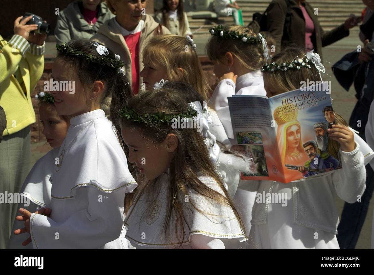 Polonia; ragazze in abiti bianchi di comunione e una corona sulla testa. La ragazza è avvincita, assorbita nella lettura. Mädchen in weißen Kommunionkleidern. Foto Stock