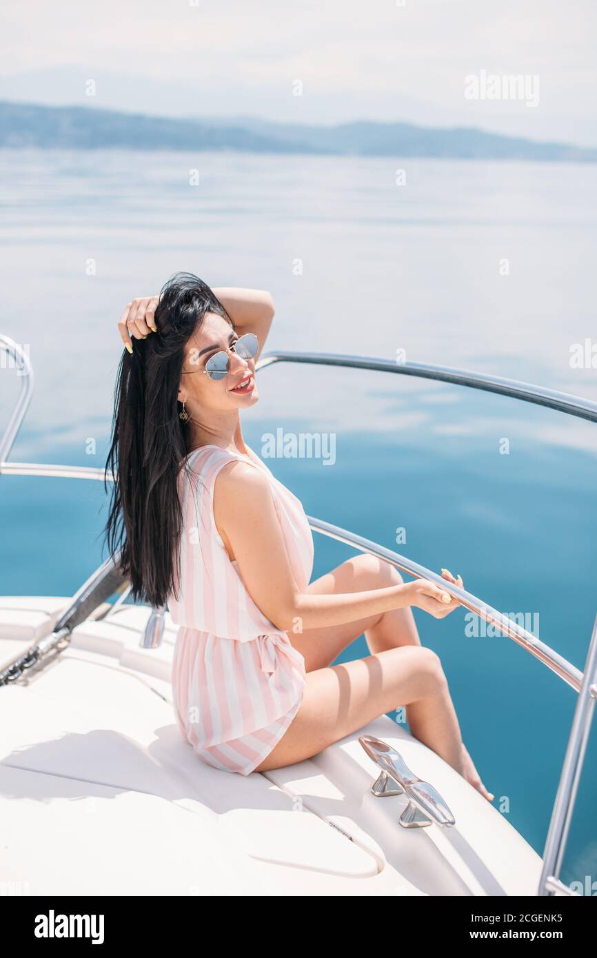 Giovane, attraente e ricca imprenditrice caucasica si impegna con uno yacht, avente fotossesion su una barca di lusso in mare al giorno d'estate e di sole Foto Stock