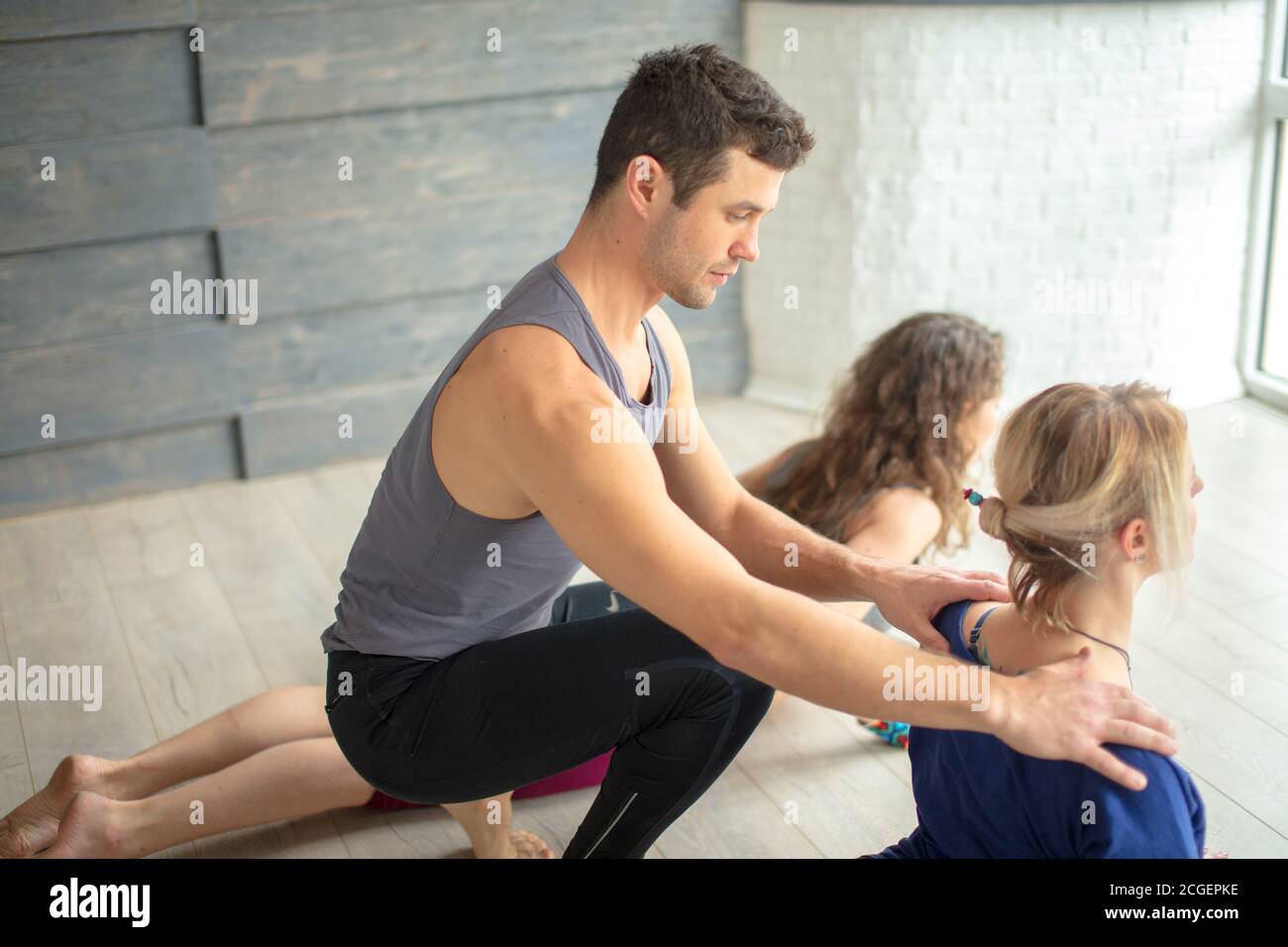 Atletico uomo Yoga istruttore di yoga insegnare yoga a tre giovani donne in palestra. Foto Stock