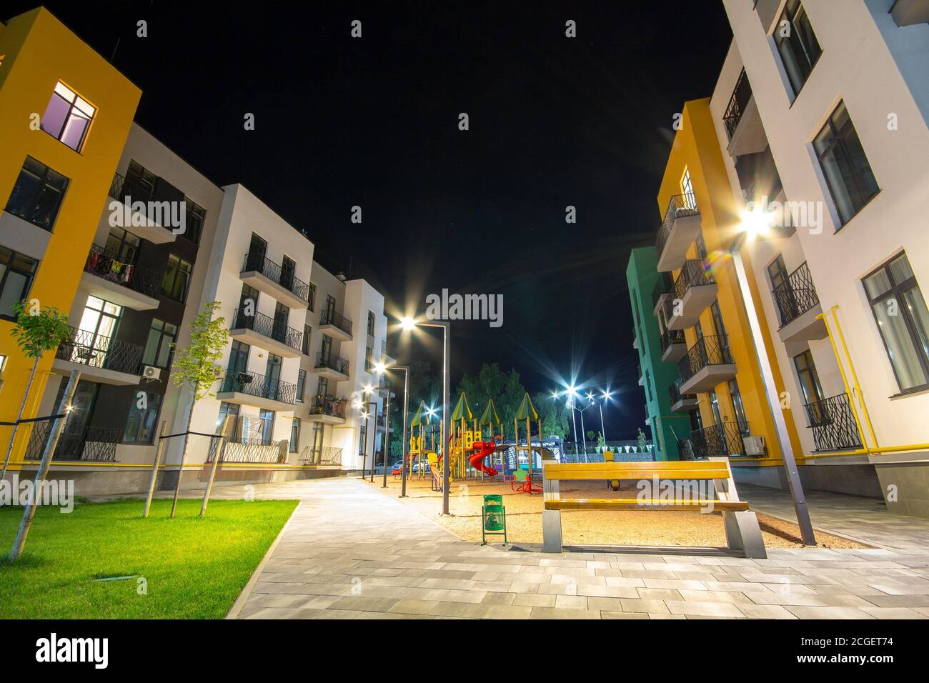 Cortile tra edifici residenziali con panca vuota in legno e moderno appartamento. Sviluppo immobiliare. Foto Stock