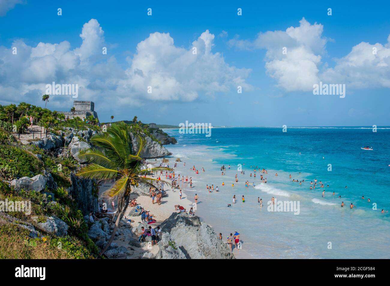 Vista della spiaggia con i turisti e El Castillo (castello) a Tulum, che è il sito di una città murata pre-colombiana Maya lungo la costa orientale del Foto Stock
