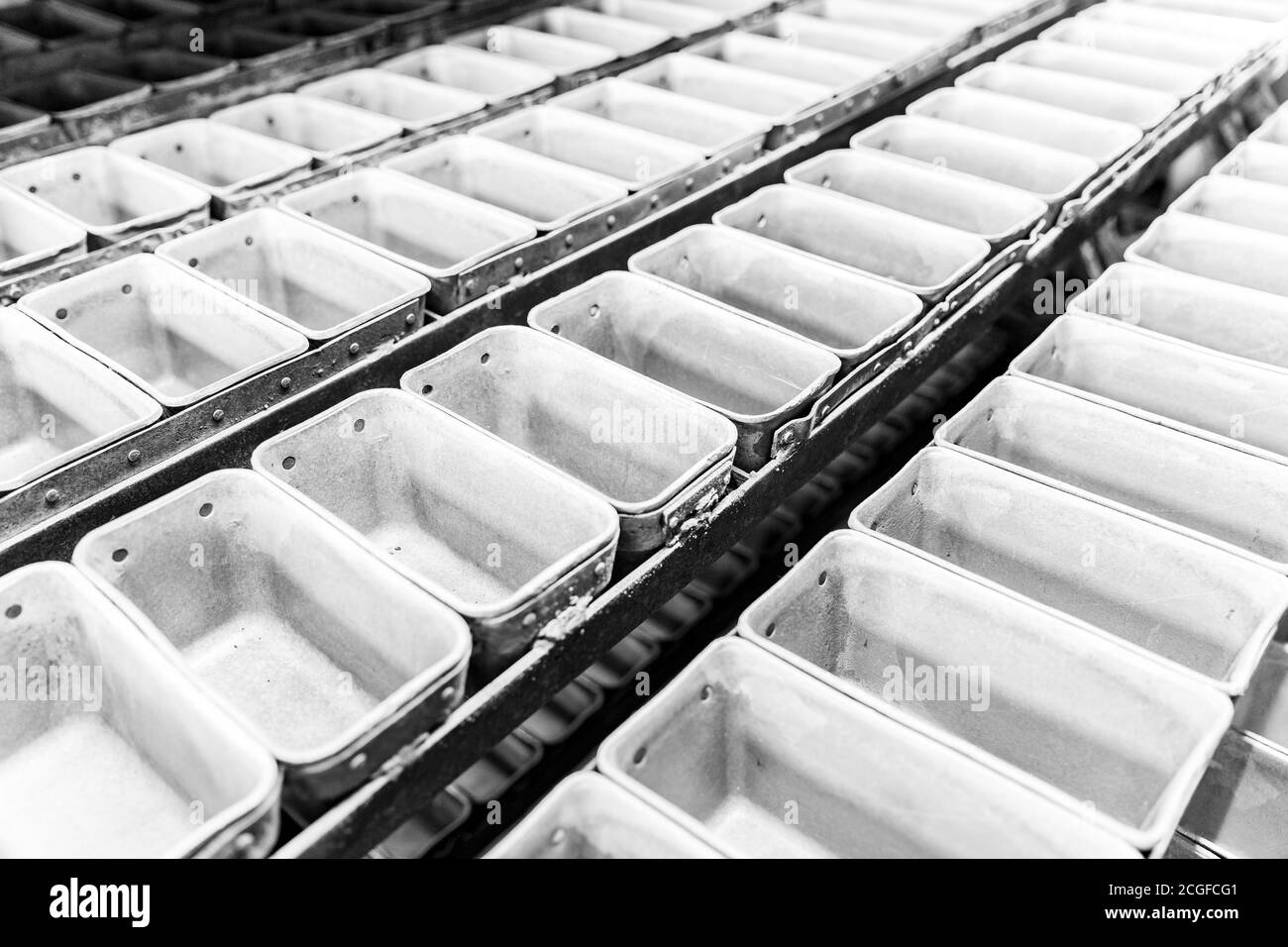 Linea automatizzata per prodotti da forno industriali. Riempimento di stampi metallici per la cottura del pane Foto Stock
