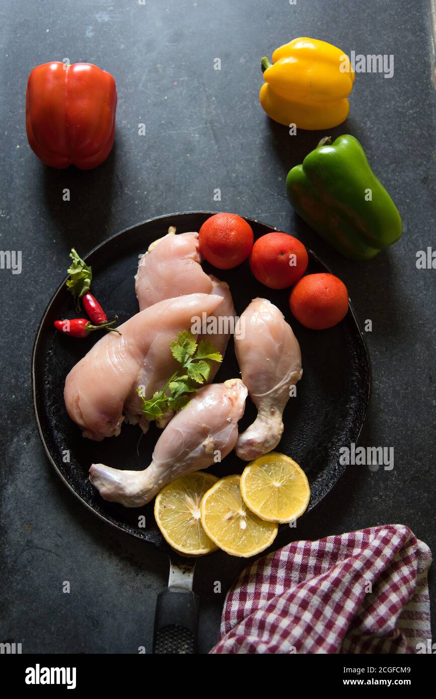 Filetti di pollo freschi e verdure crude su una padella nera con uso di fuoco selettivo. Foto Stock