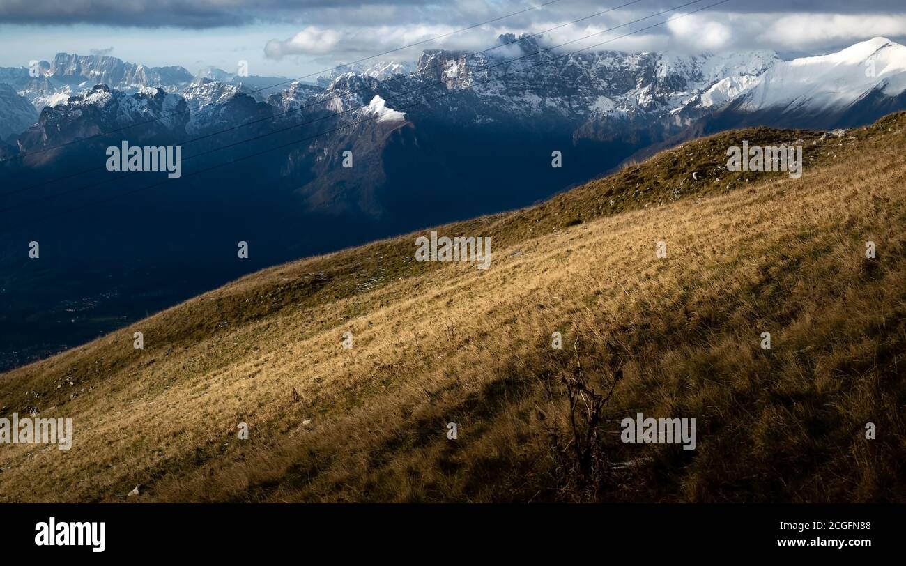 Pendio invernale di montagna. Sullo sfondo, le creste delle montagne innevate e illuminate dal sole. Alpe del Nevegal, Belluno, Italia Foto Stock