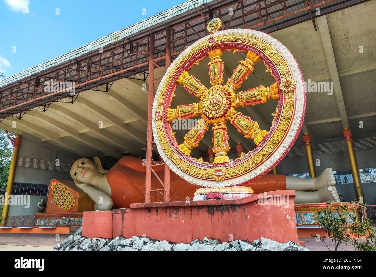 La ruota del Dharma di fronte al più grande Buddha reclinato della Malesia all'interno di Wat Phothivihan, un tempio buddista di Kelantan, Malesia Foto Stock