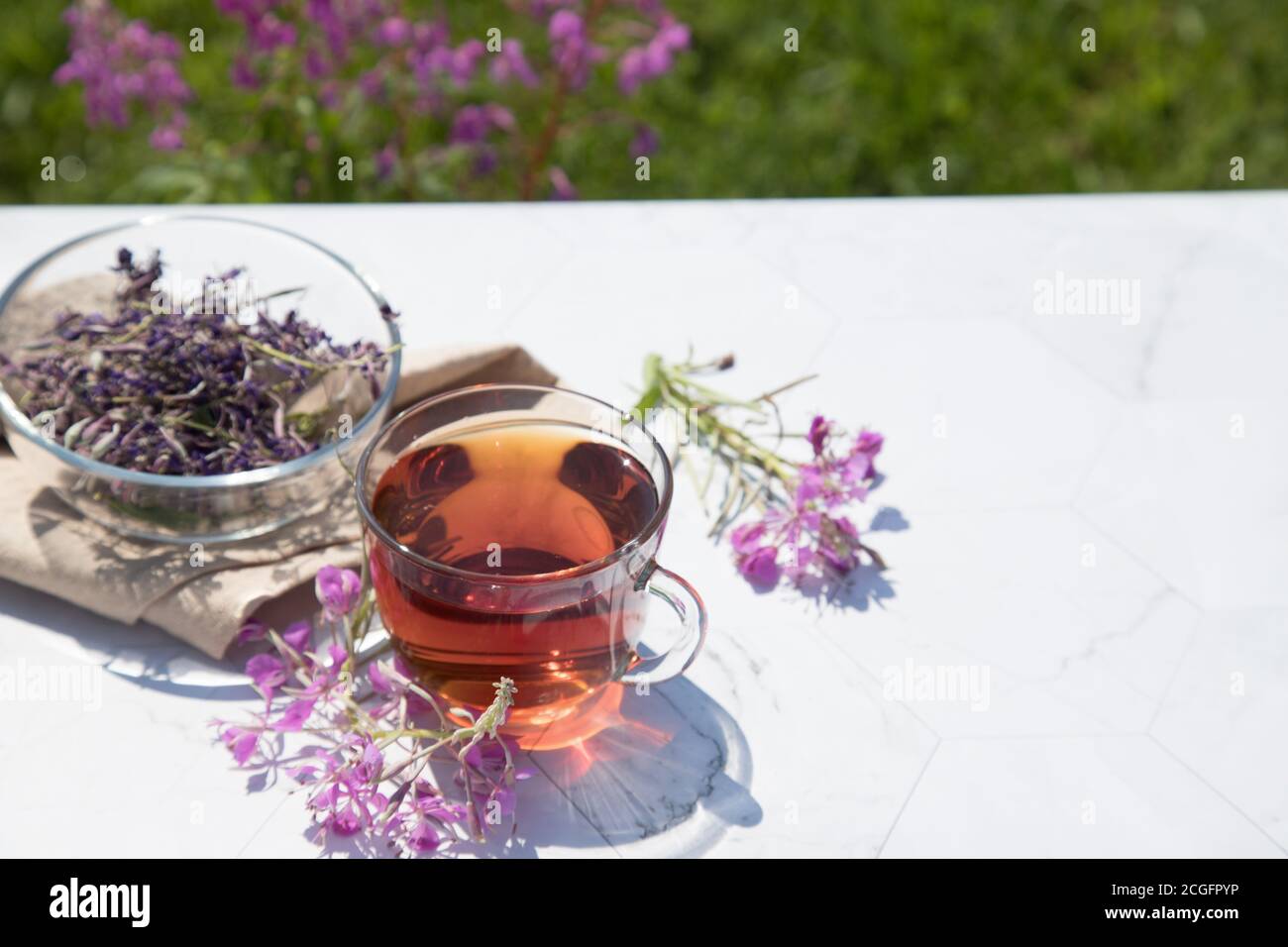 Chamaenerion Angustifolium tè (cipresso, salice grande, salice rosa) con fiori secchi e freschi per la decorazione in tazze di vetro su uno sfondo chiaro. Conce Foto Stock