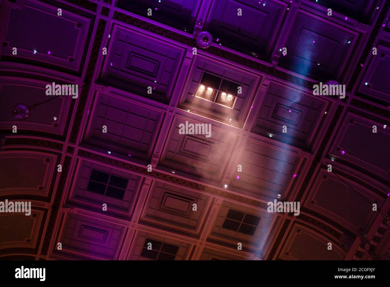 Luci colorate suonano attraverso il soffitto ornato di un vecchio teatro durante un concerto musicale. Foto Stock