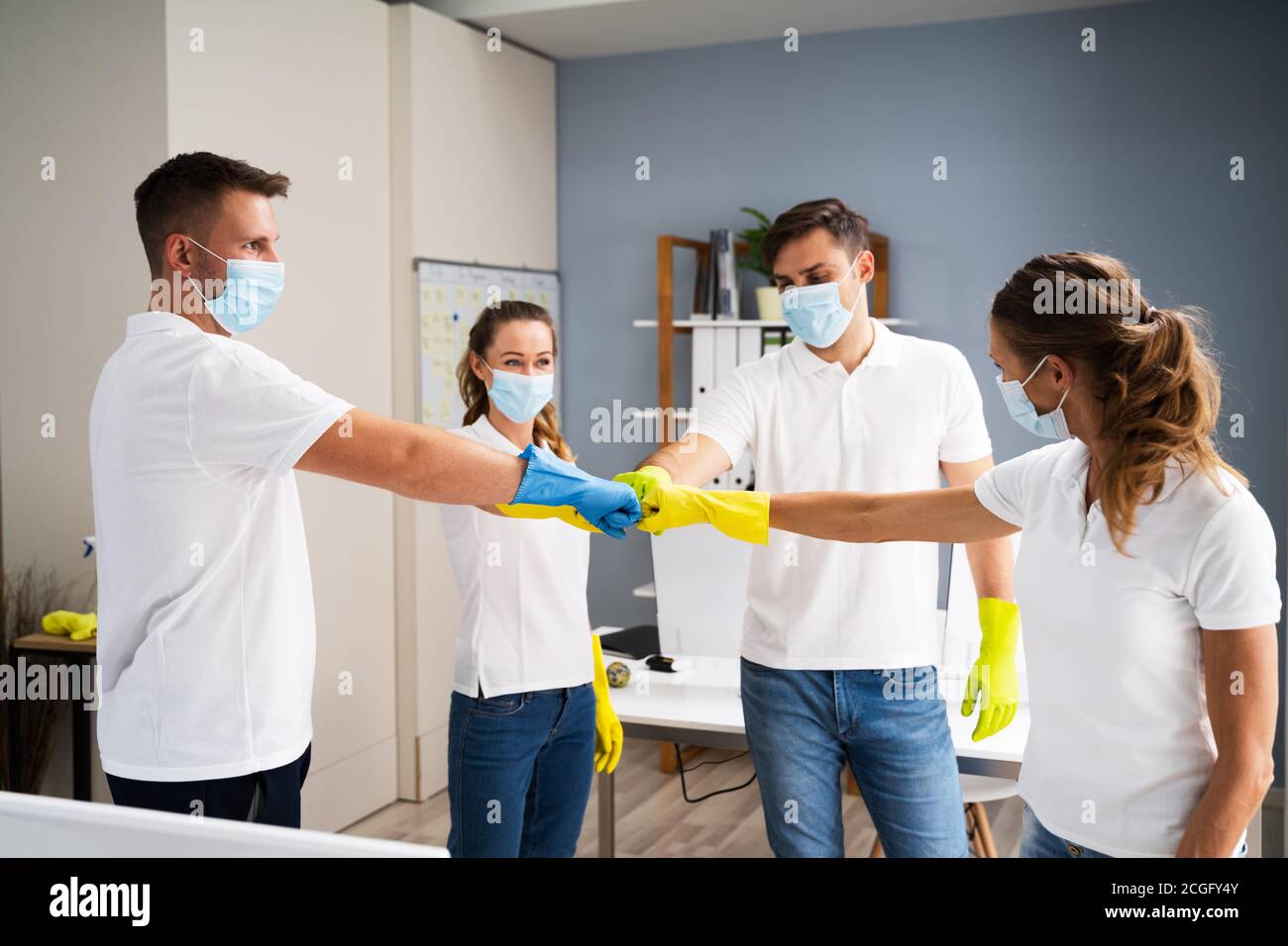 Ufficio professionale pulizia Janitor Team Spirit e Huddle con viso Maschere Foto Stock