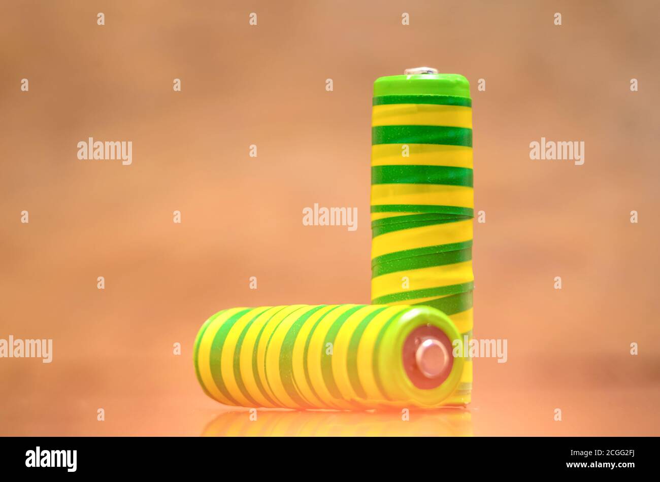 Due batterie giallo-verde si chiodano su sfondo di legno Foto Stock