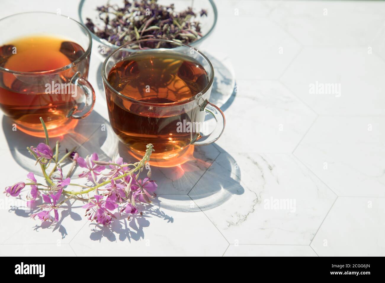 Chamaenerion Angustifolium tè (cipresso, salice rosa, Ivan-tea) con fiori secchi e freschi per la decorazione in due tazze di vetro su uno sfondo chiaro, dri Foto Stock