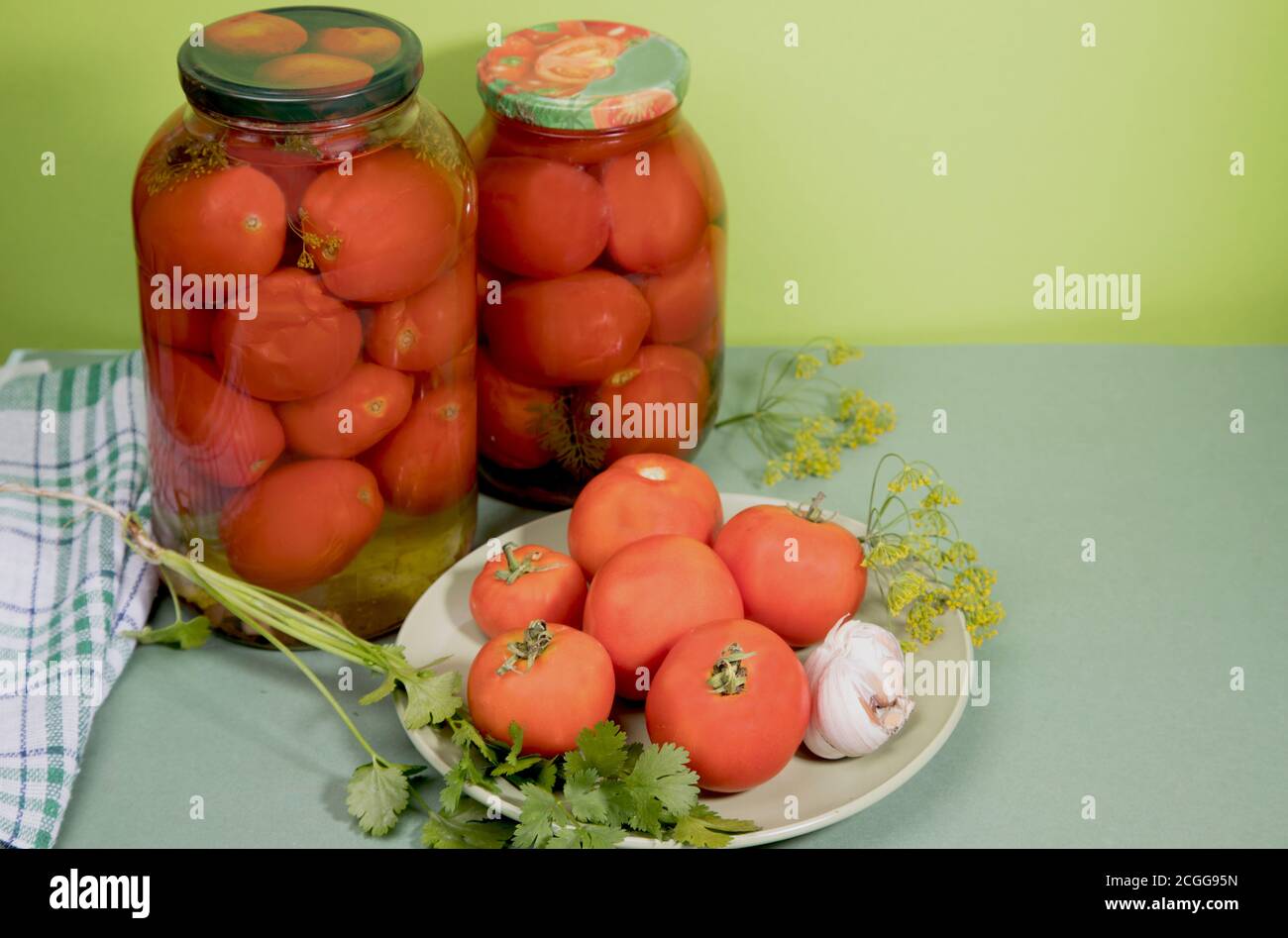 Pomodori marinati in vasi . I pomodori freschi con aglio ed erbe sono su un piatto. Orientamento orizzontale. Foto Stock