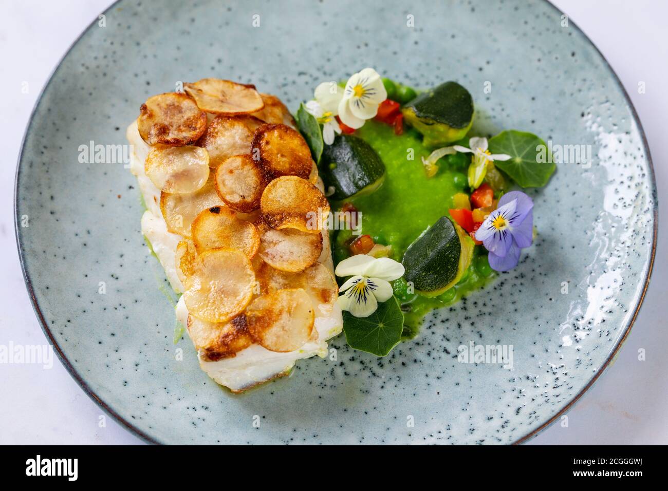 Filetto di pesce bianco con scala di patate, purea di piselli e verdure estive Foto Stock