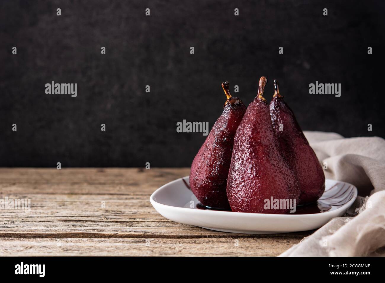Pere in camicia in vino rosso su tavola di legno. Spazio di copia Foto Stock