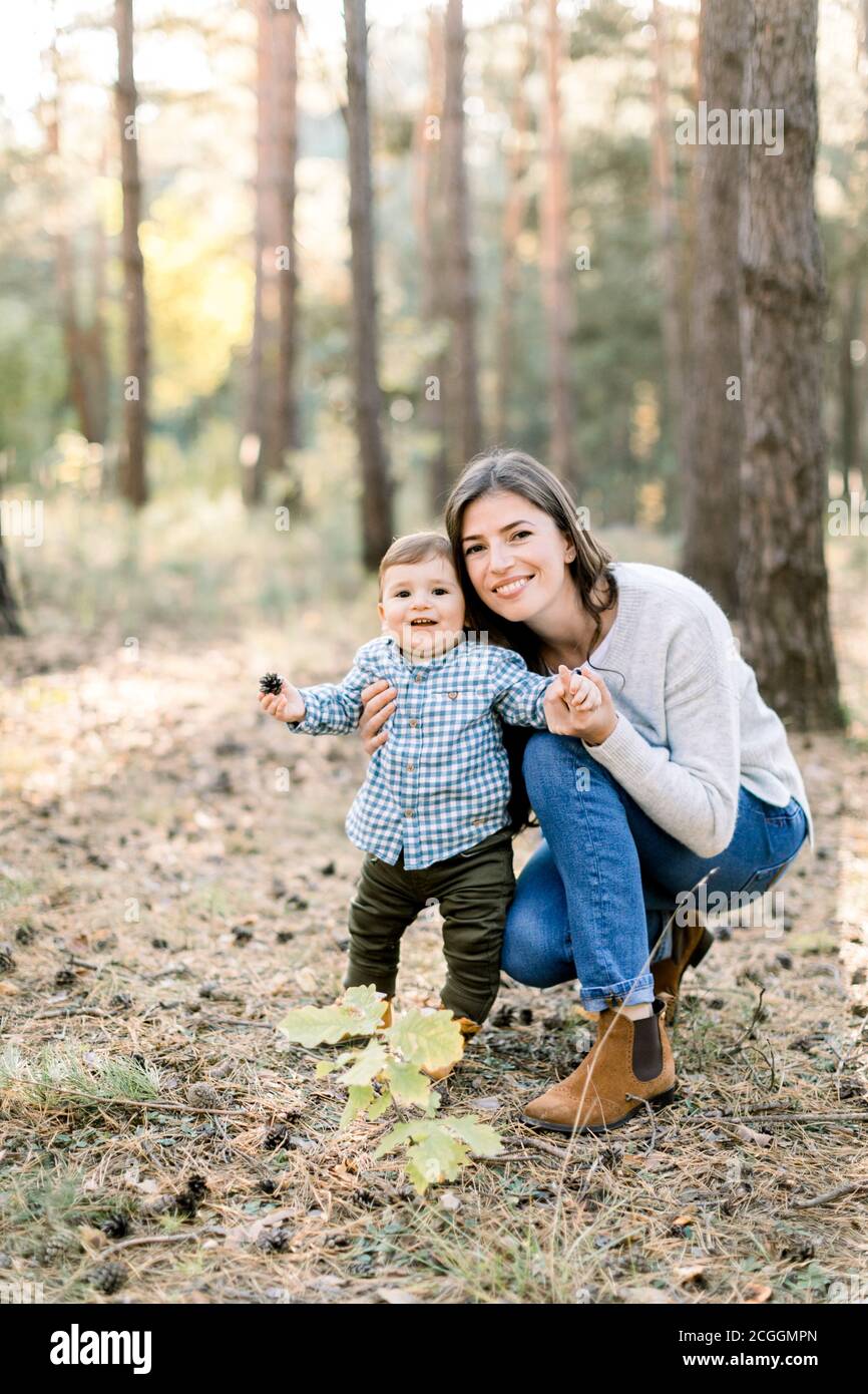 Ritratto autunnale all'aperto di giovane bella madre donna in posa in pineta d'autunno con il suo bel figlio carino, ridendo insieme. Foto Stock