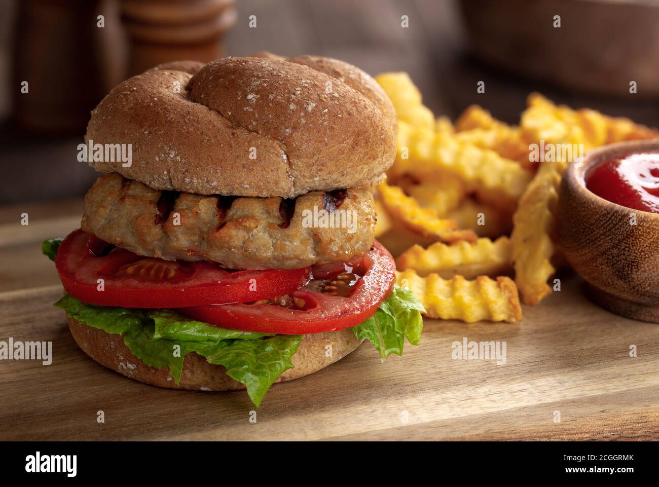 Primo piano di hamburger di tacchino alla griglia con pomodoro e lattuga panino di grano intero Foto Stock