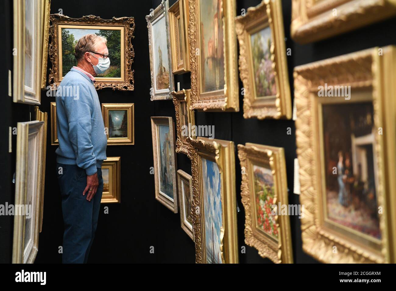 Un cliente guarda i dipinti della Petworth Park Antiques and fine Art Fair, presso la Petworth House, nel West Sussex. Foto Stock