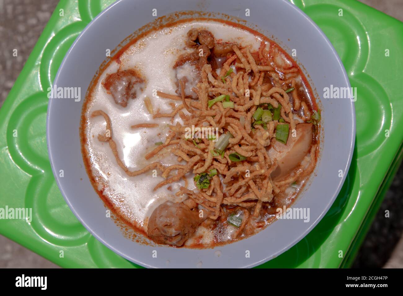 Ricetta tradizionale di Khao Soi, zuppa di Noodle al curry in stile Tailandese settentrionale con pollo in ciotola bianca. Messa a fuoco selettiva. Foto Stock