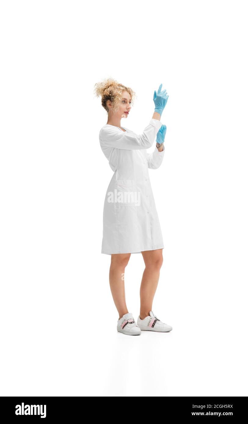 Ritratto di dottore, infermiera o cosmetologa in uniforme bianca e guanti blu su sfondo bianco dello studio. CopySpace per l'annuncio. Concetto di salute e medicina, bellezza, self-care. Foto Stock