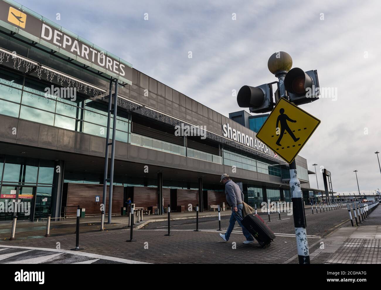 Aeroporto di Shannon, Irlanda - 21 novembre 2016: Uomo che cammina con i bagagli verso la costruzione delle partenze dell'aeroporto di Shannon nella Repubblica d'Irlanda. Foto Stock