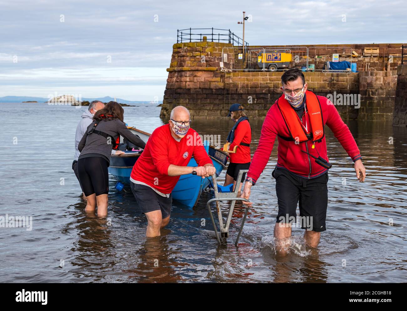 L'equipaggio costiero che indossa maschere facciali lancia lo skiff di St Ayle dal rimorchio della barca, North Berwick, East Lothian, Scozia, Regno Unito Foto Stock