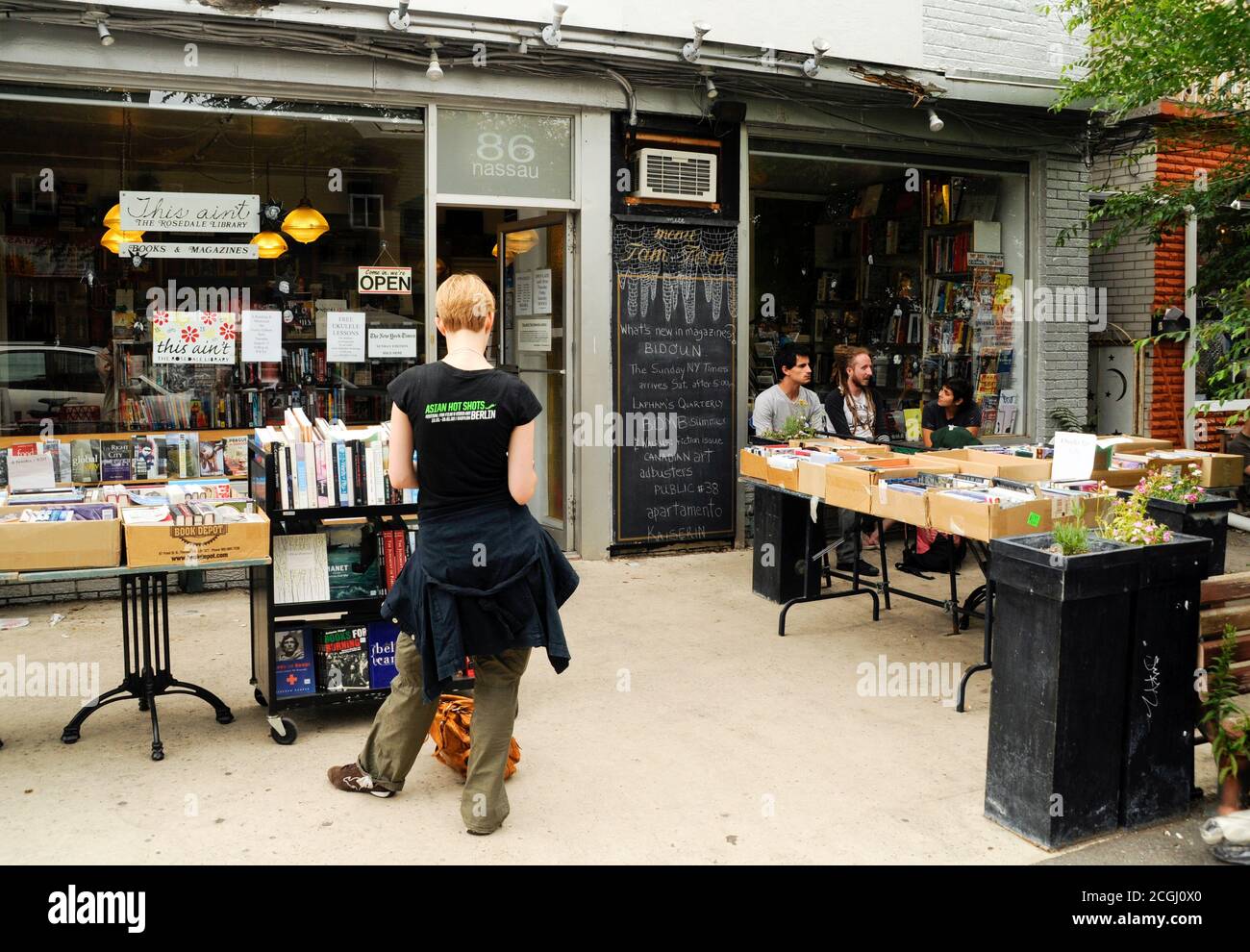 Una shopper donna cerca libri in vendita al di fuori di una libreria indipendente nel quartiere Kensington-Market del centro di Toronto, Ontario, Canada. Foto Stock