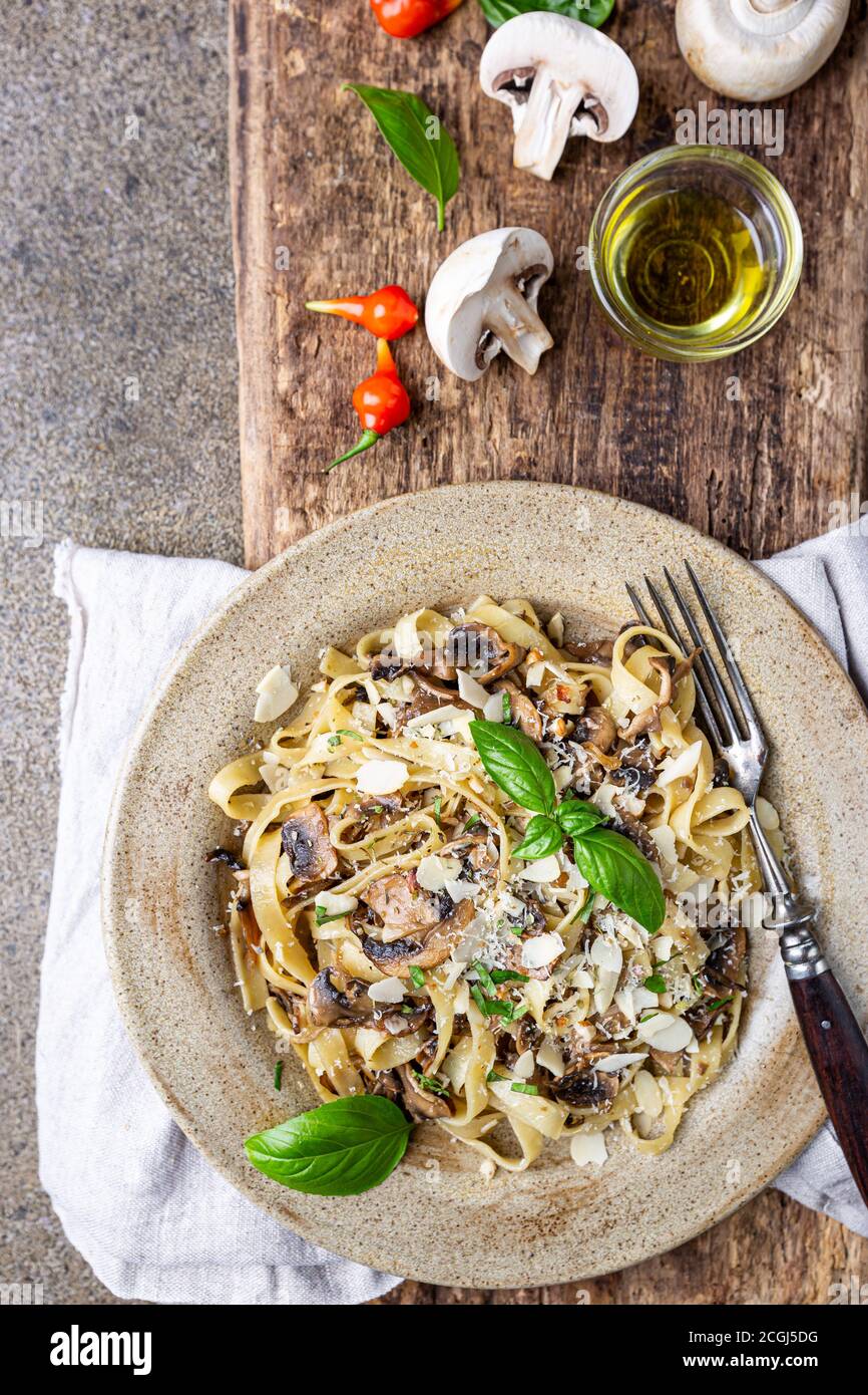 Tagliatelle con funghi e formaggio e foglia di basilico sulla piastra, vista dall'alto Foto Stock