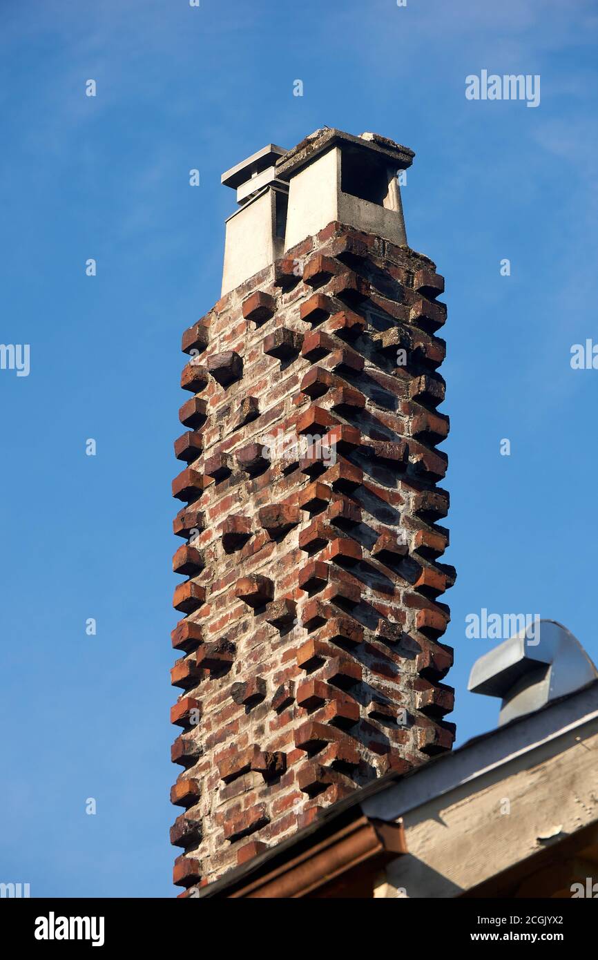 Camino in muratura di mattoni rossi con mattoni sporgenti decorativi sul tetto di una casa Foto Stock