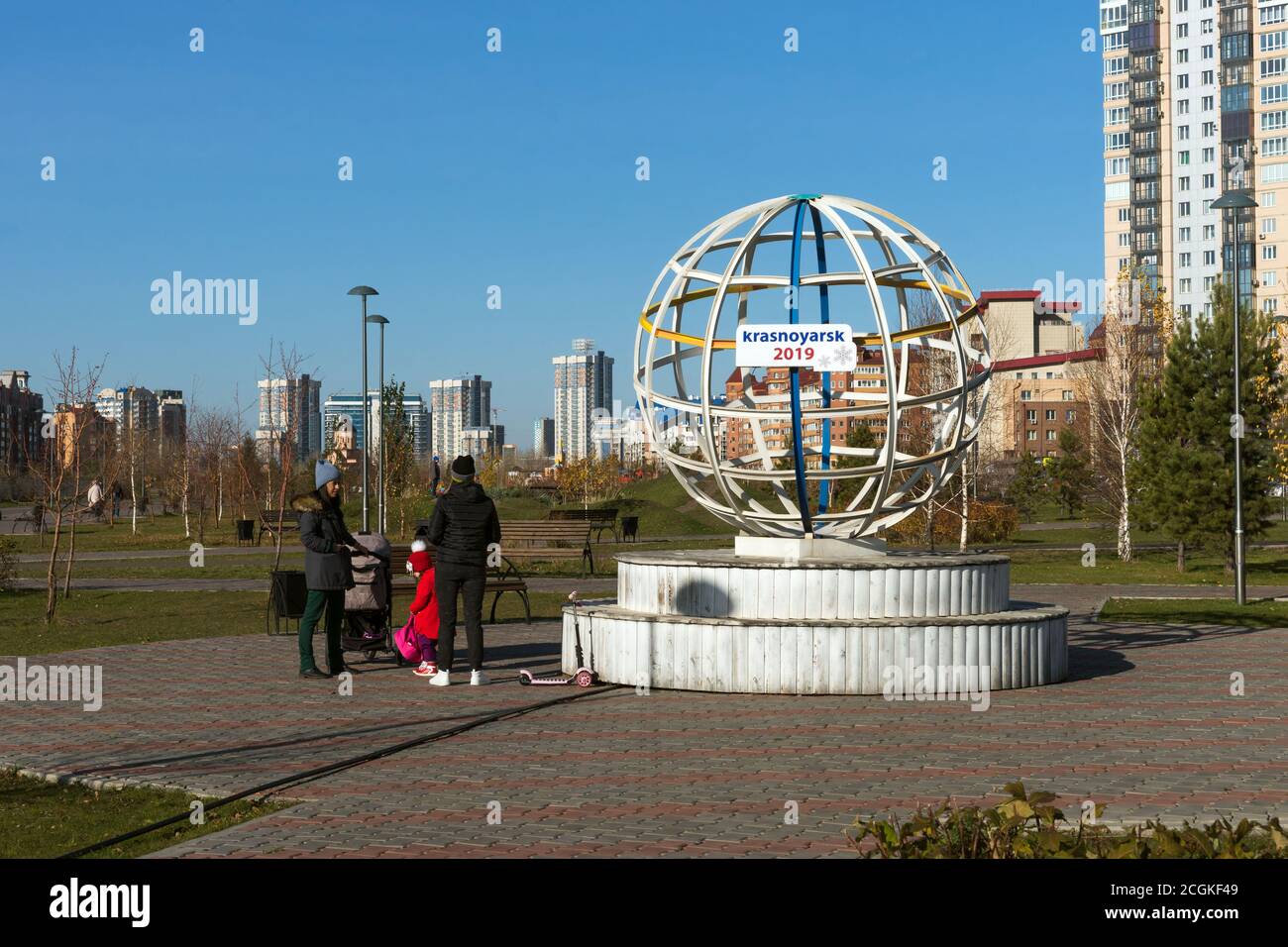 La gente cammina nel parco, vicino alla scultura rotonda in metallo, installata nel parco della città di Krasnoyarsk per l'Universiade invernale 2019. Foto Stock