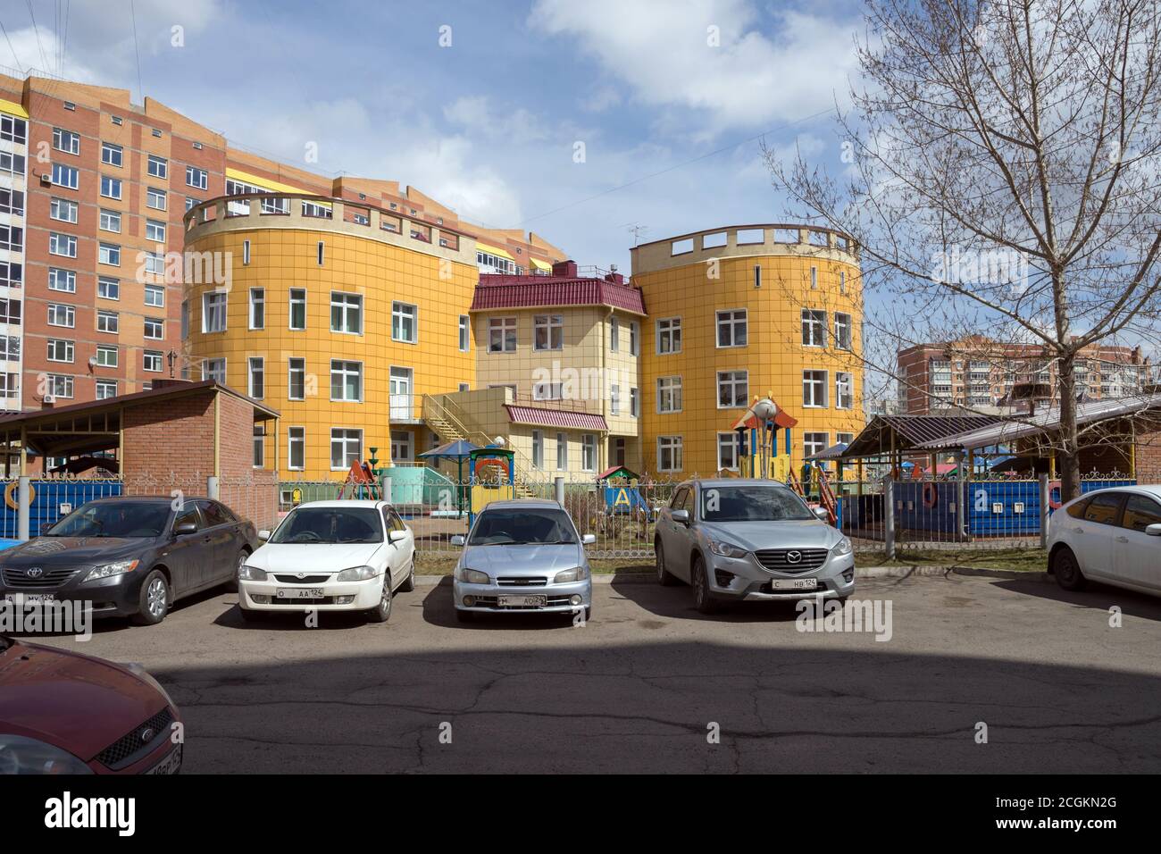 La costruzione del Kindergarten in un quartiere residenziale della città di Krasnoyarsk con auto parcheggiate di fronte, sullo sfondo di un resi Foto Stock