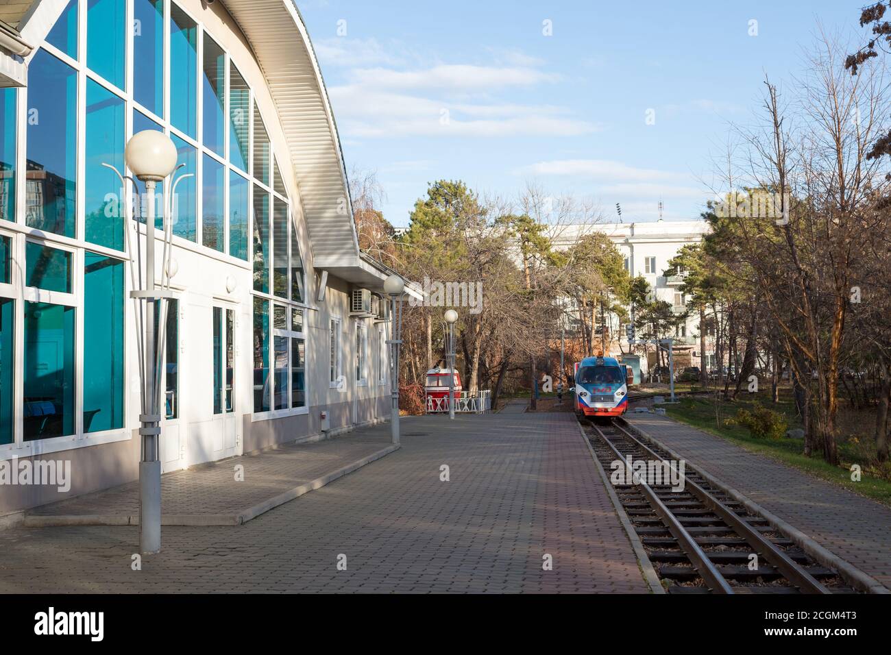 La locomotiva della ferrovia per bambini di Krasnoyarsk si trova sulle rotaie vicino alla stazione di Yubileinaya nel Parco Centrale in una giornata di sole autunno. Foto Stock
