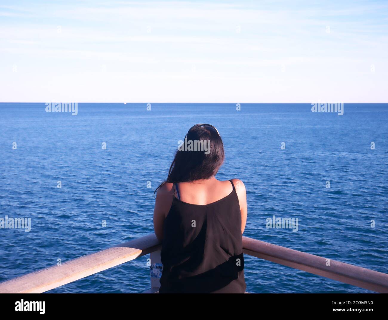Donna afro-asiatica vista da dietro guardando il mare Foto Stock
