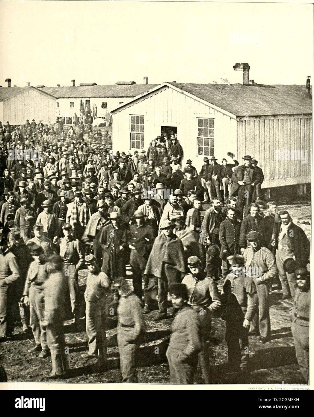 . La storia fotografica della Guerra civile : in dieci volumi . CAMP DOUGLAS, VICINO A CHICAGO in primo piano, si erge un sergente confederato con rotoli di prigionieri nelle sue mani. Era l'abitudine dei prigionieri di scegliere tra il loro proprio numero di pasticci-sergente. Queste centinaia di uomini sono una parte delle migliaia confinate a Camp Douglas. Le caserme sono state racchiuse da una recinzione per confinare i prigionieri confederati presi a Forts Donelson ed Henry, e nuove barracche sono state successivamente costruite. Le caserme erano edifici di legno novanta per ventiquattro piedi, di cui venti piedi sono stati tagliati per il fossato Foto Stock