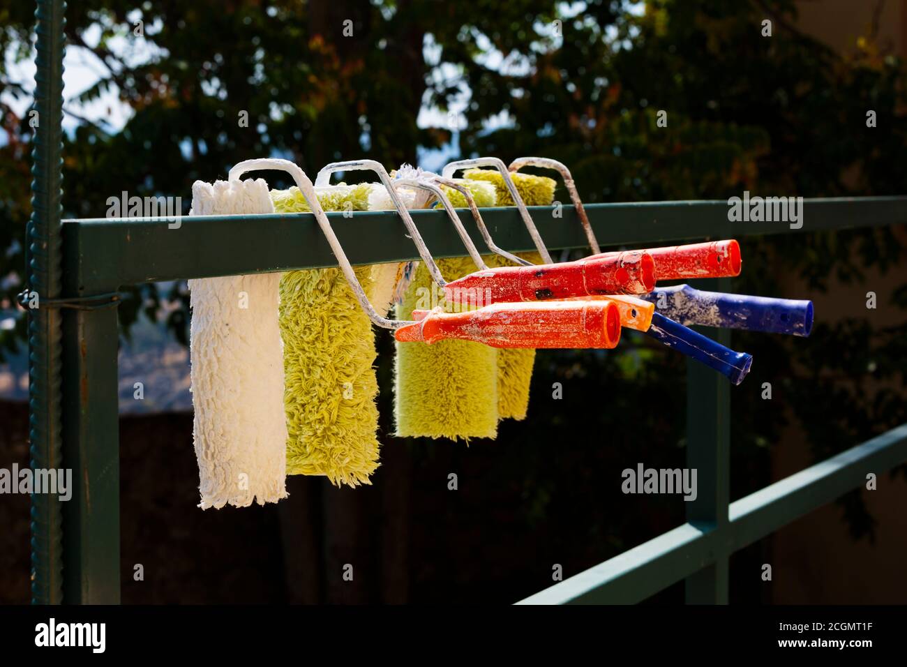 Set di rulli di vernice appesi per asciugare su a. recinzione Foto Stock