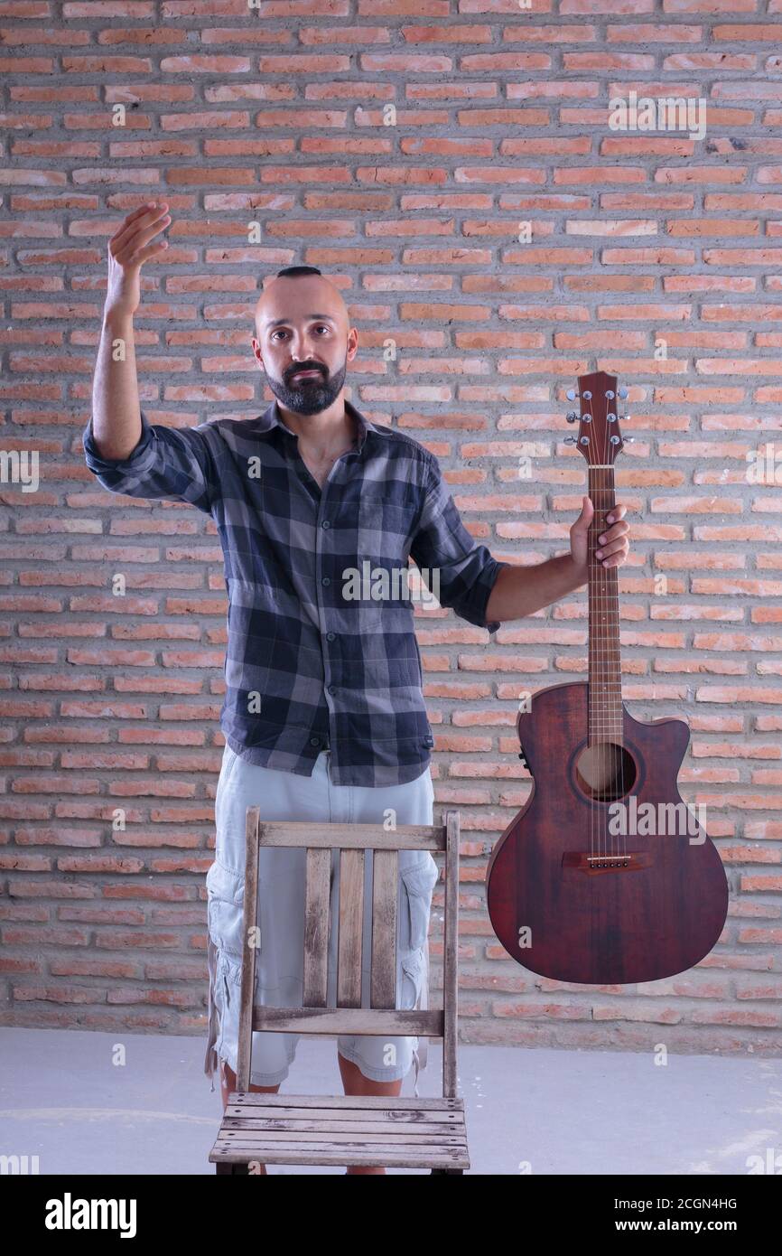 Giovane adulto maschio che tiene una chitarra acustica dopo un'esibizione. Foto Stock