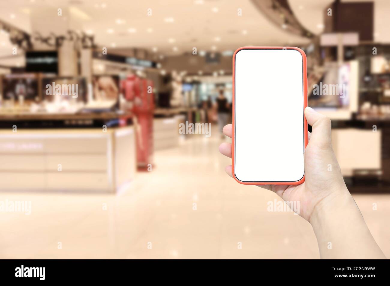 Mano di un uomo che tiene il dispositivo smartphone sullo sfondo del centro commerciale e che ha uno spazio di copia bianco sullo schermo. Foto Stock