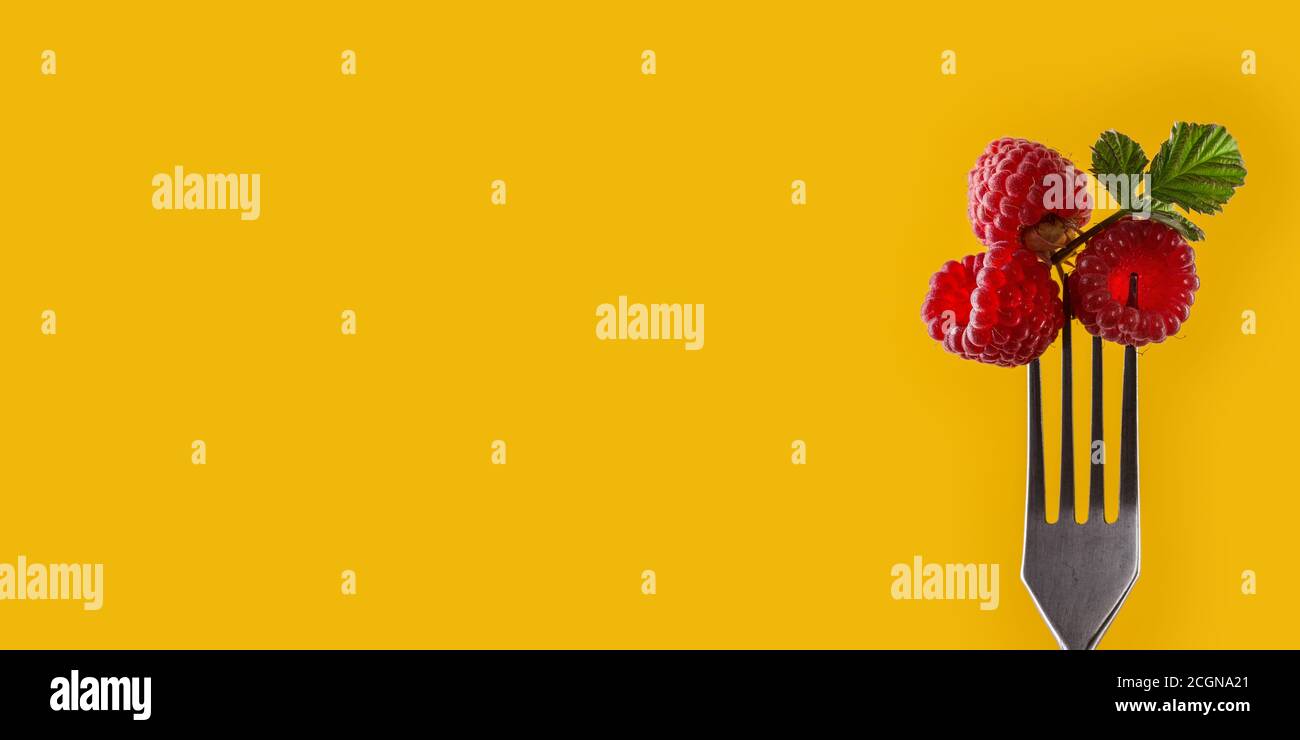 Lamponi su forchetta su sfondo giallo. Concetto di alimentazione sana. Cibo estivo. Stile minimalista alla moda. Prodotti naturali biologici. Stile di vita sano. Foto Stock