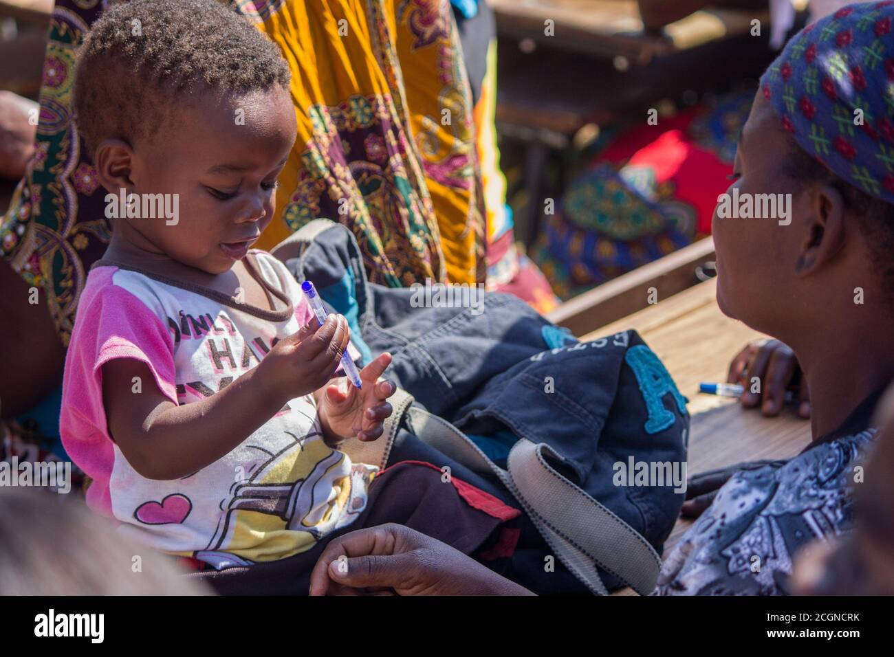 Bambina giovane che tiene una penna di fronte a sua madre Foto Stock