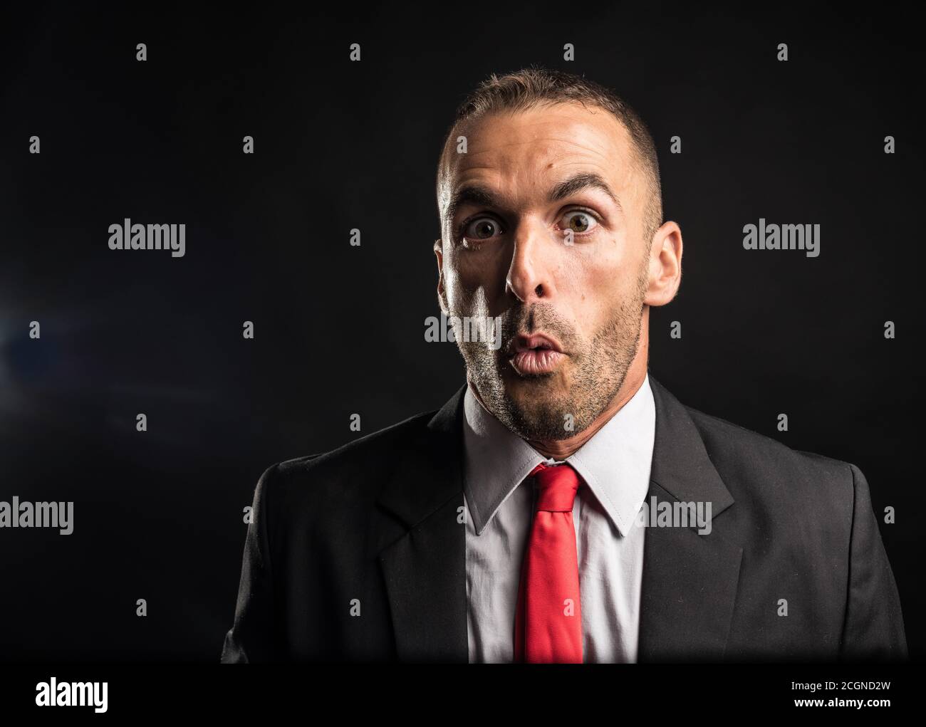 Uomo sorpreso nel vestito. Sfondo nero, primo piano. Foto Stock
