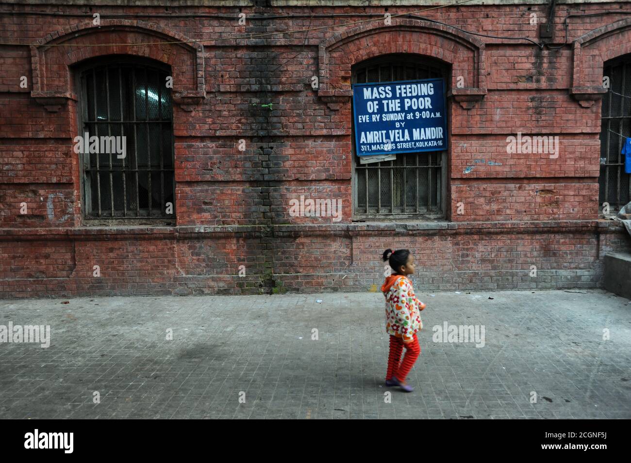 01.12.2011, Kolkata (Calcutta), Bengala Occidentale, India, Asia - UNA ragazza passa davanti al sito dell'alimentazione di massa dei poveri Amrit vela Mandir (Langar). Foto Stock