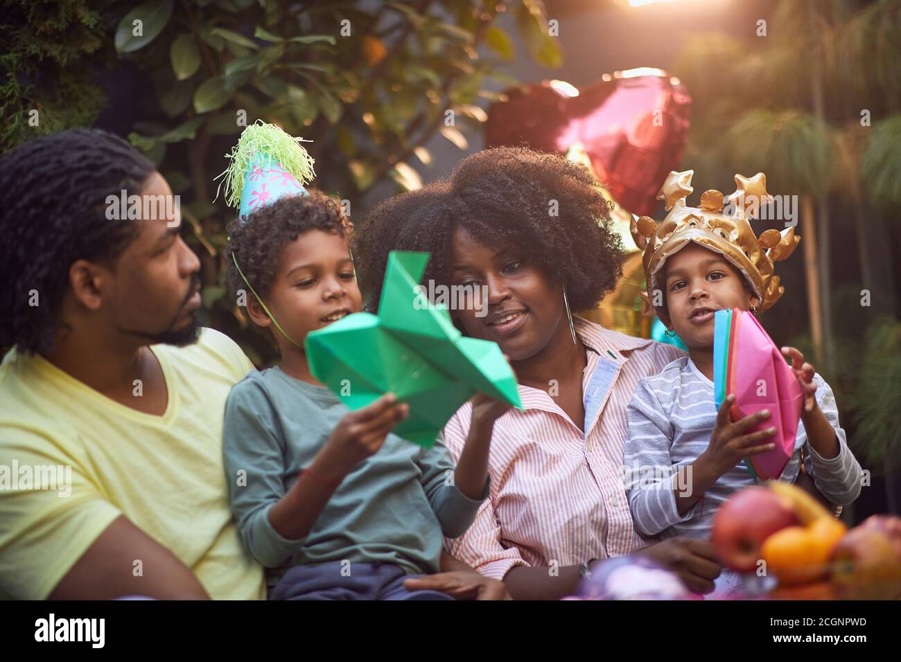 la famiglia afro-americana si è riunita in festa di compleanno giocando insieme alla carta cappello e barche Foto Stock