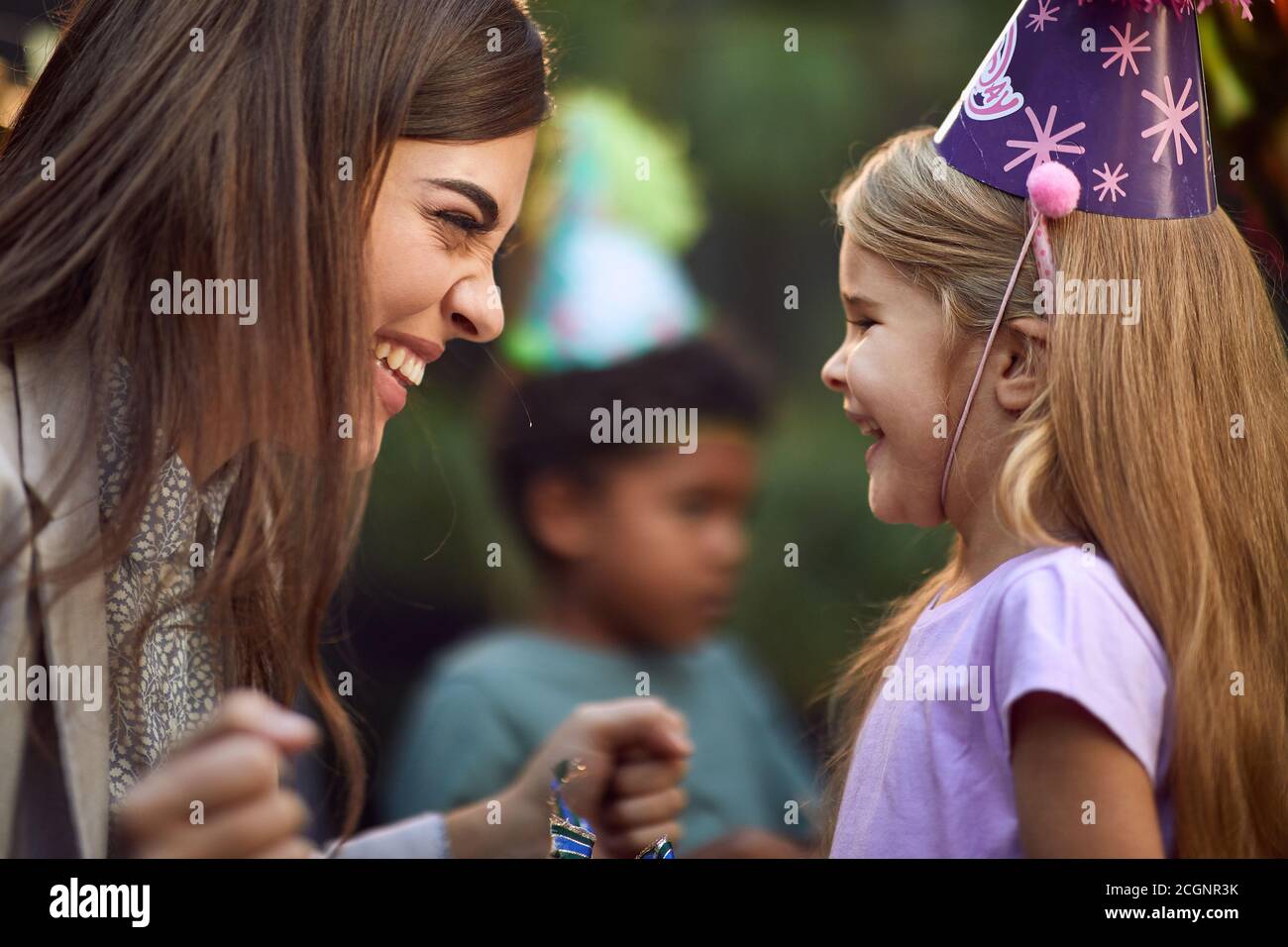 allegra bella bruna sorridente con carina bambina bionda a. festa di compleanno Foto Stock