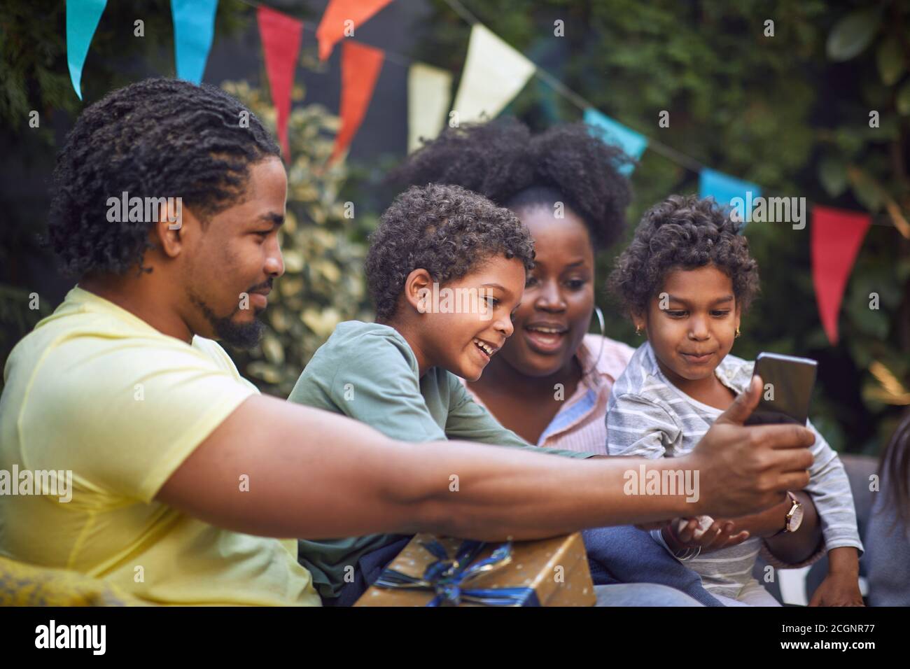 giovane padre afro-americano che mostra qualcosa alla sua famiglia su di lui telefono cellulare Foto Stock