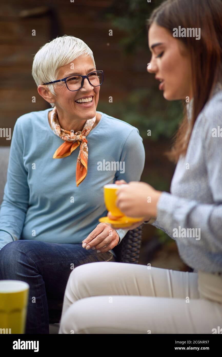 vecchia madre allegra e giovane figlia adulta che parla, bevendo caffè Foto Stock