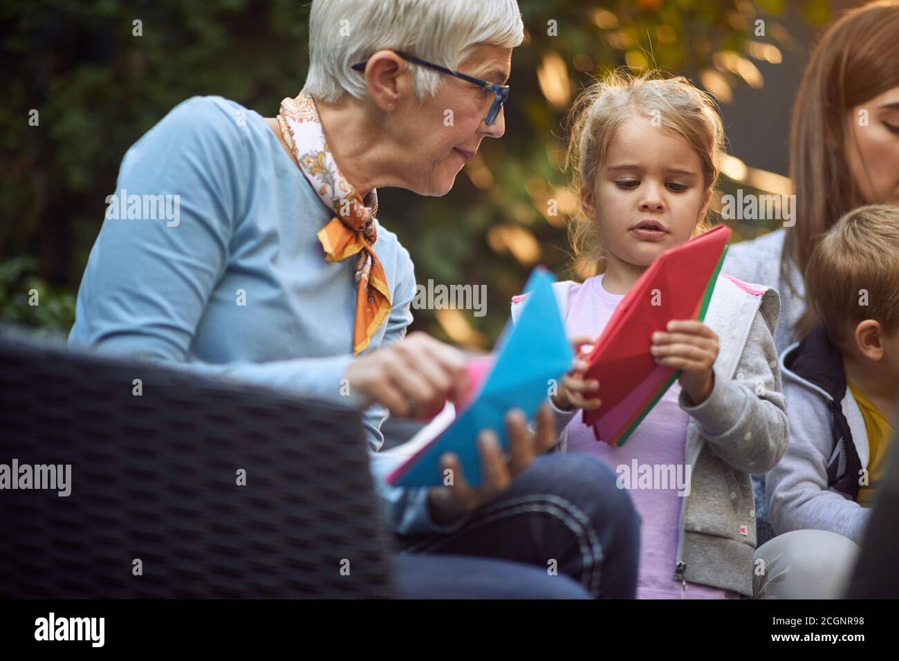 la nonna caucasica gioca con la nipote con barche di carta sedute all'esterno, focalizzate. Spazio di copia Foto Stock