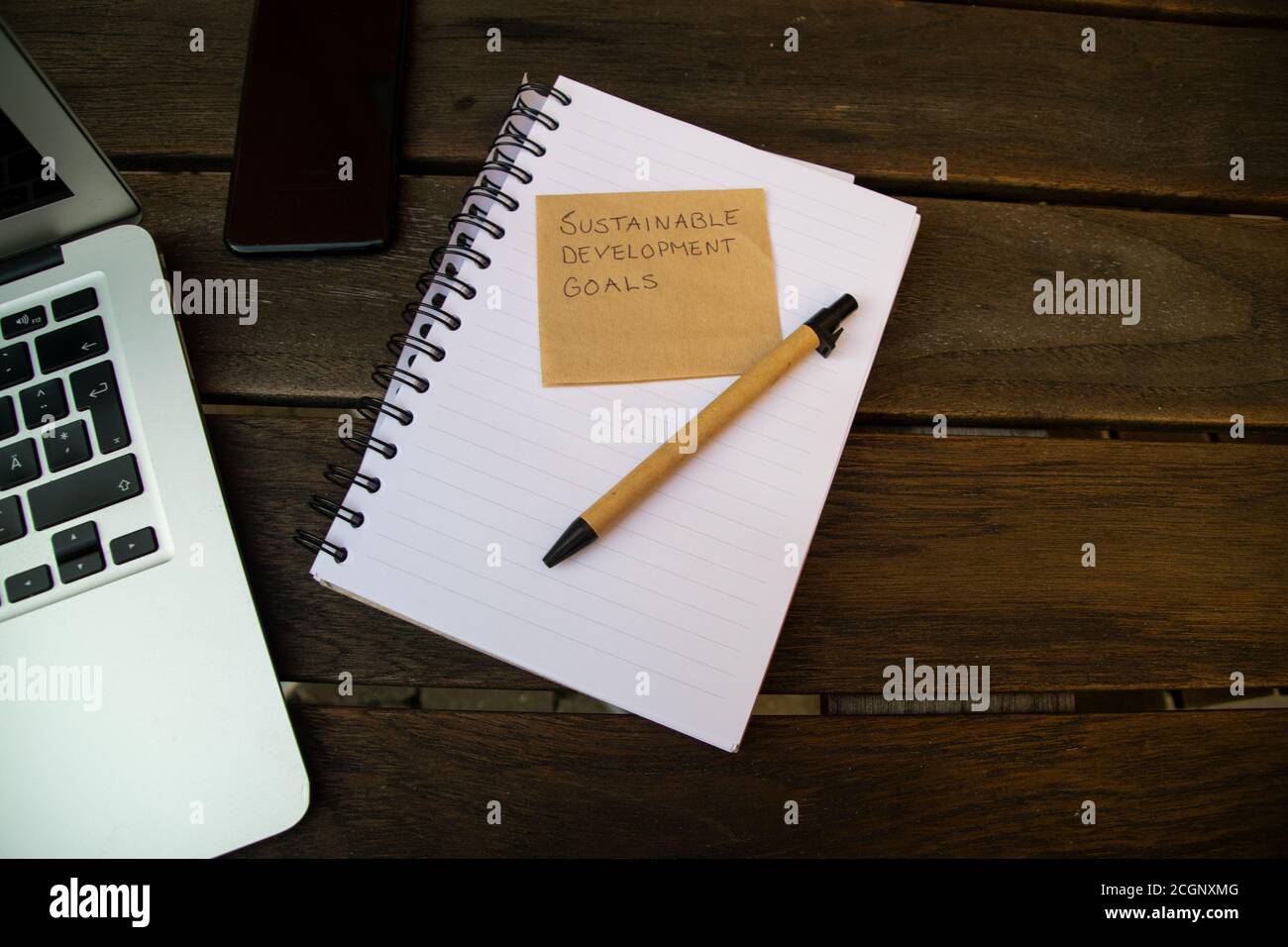 Concetto di lavorare verso gli obiettivi di sviluppo sostenibile. Nota, notebook e penna, realizzati in materiali riutilizzabili su tavolo di legno Foto Stock