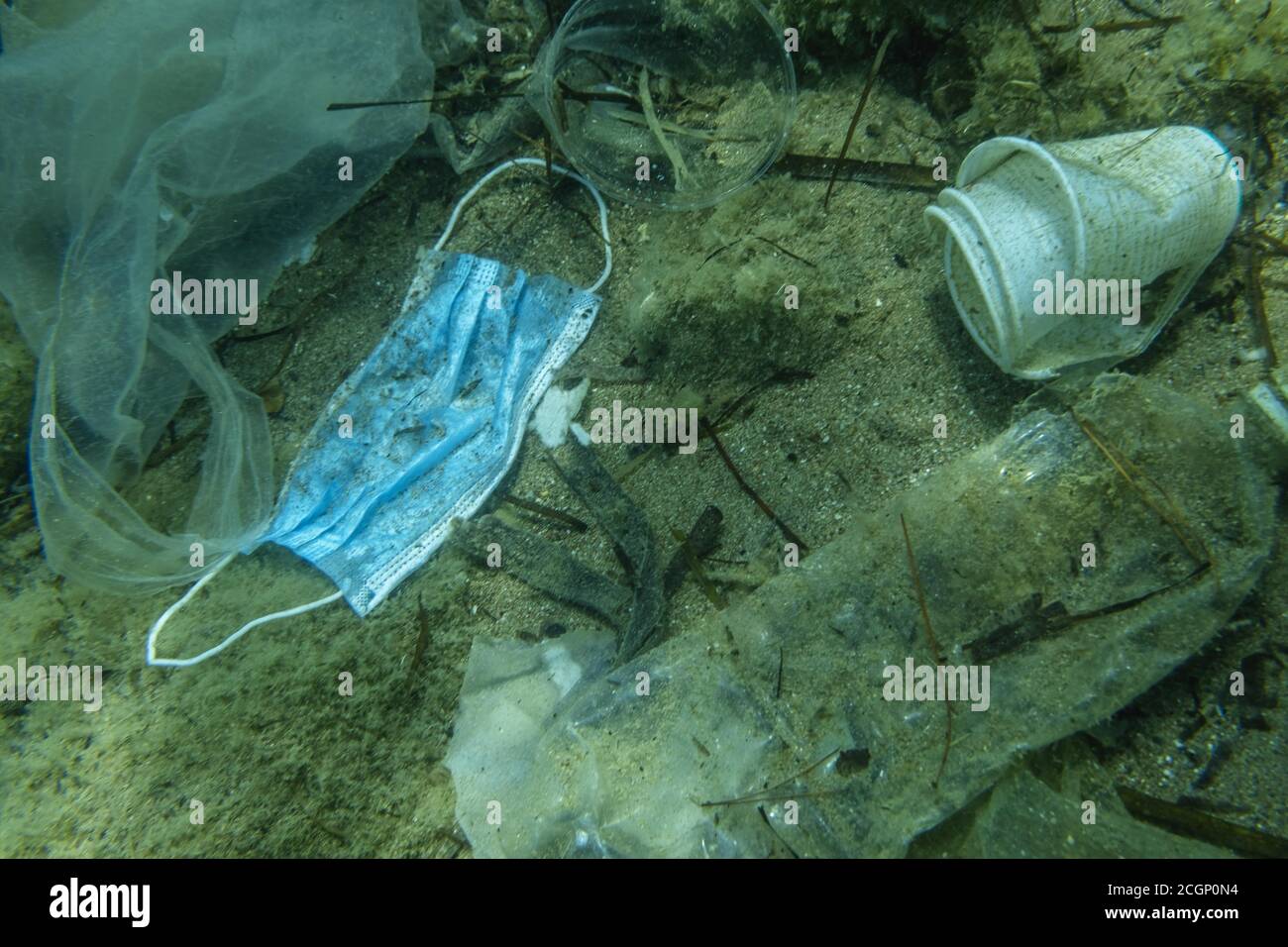 La maschera medica usata scartata si trova sul fondo marino insieme ad altri rifiuti di plastica, Becici, Budva regione, Montenegro Foto Stock