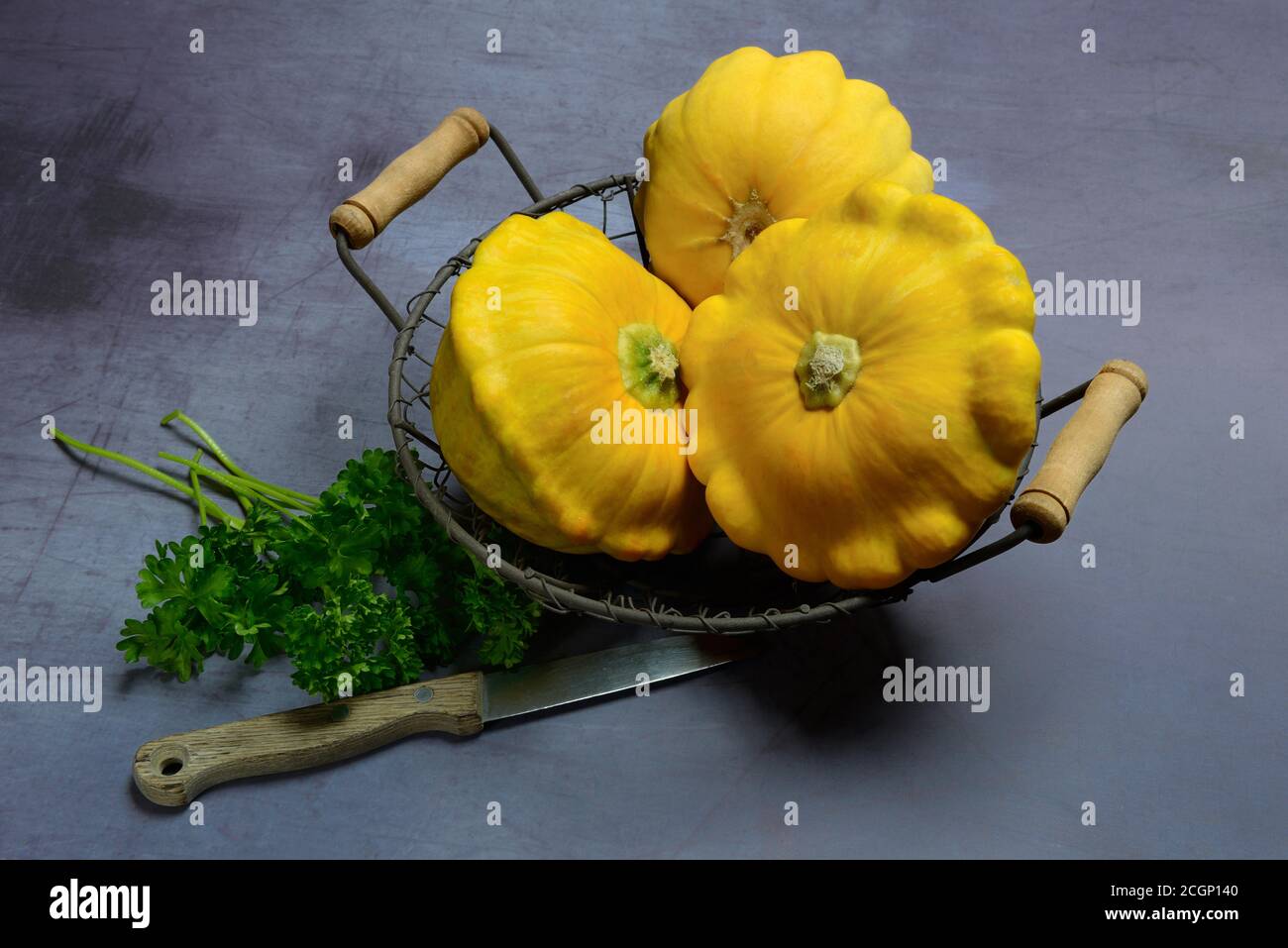 Zucche di patisson giallo in cestello di filo, prezzemolo e coltello, Germania Foto Stock